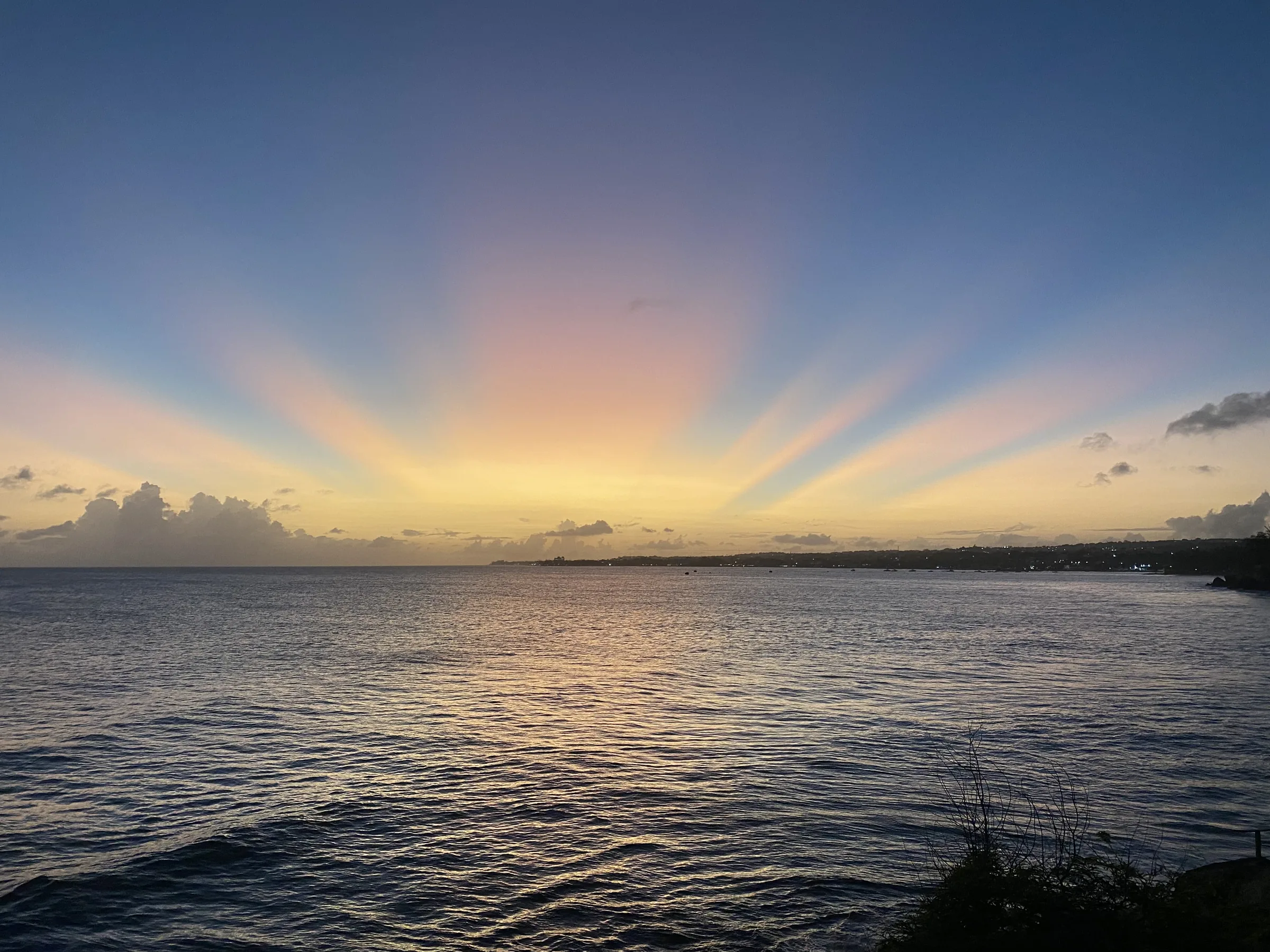 Pink and yellow sun rays fanning out over the sea along the south coast at dusk