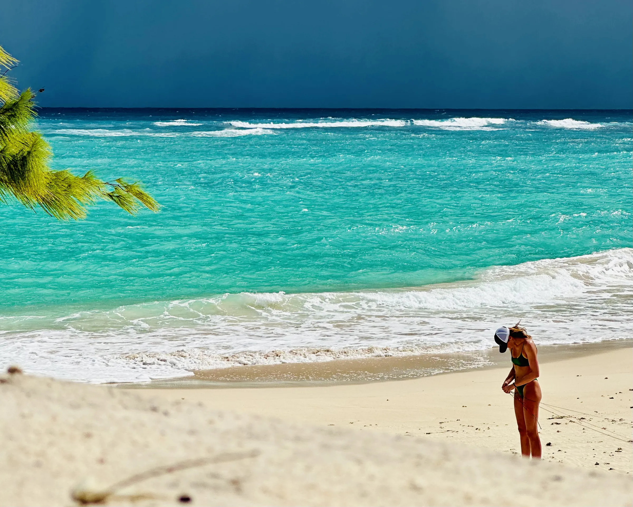 Turquoise waves rolling onto a white beach under a dark sky
