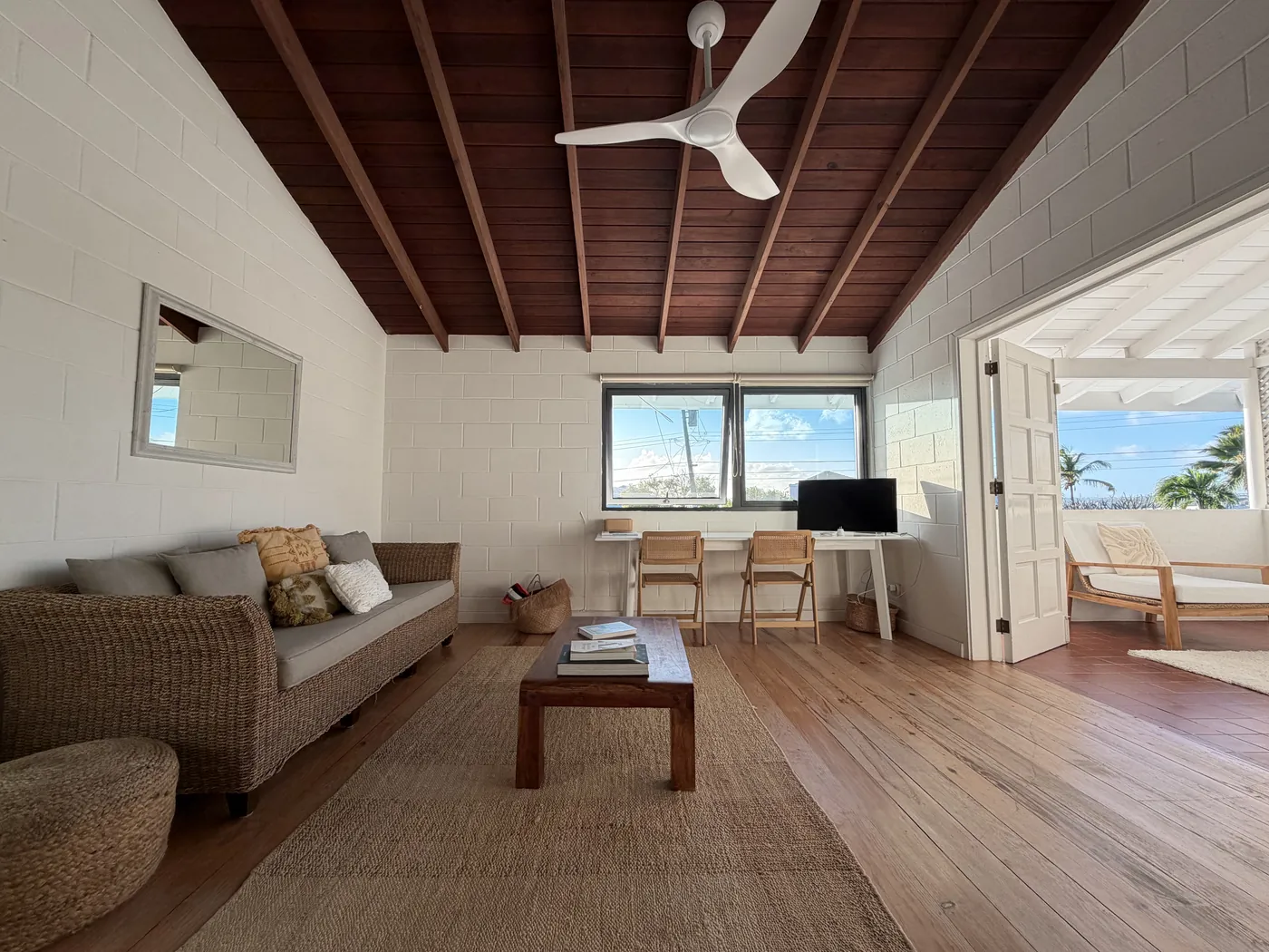 The upstairs living room with a wooden ceiling, a sofa, a desk and doors to the patio