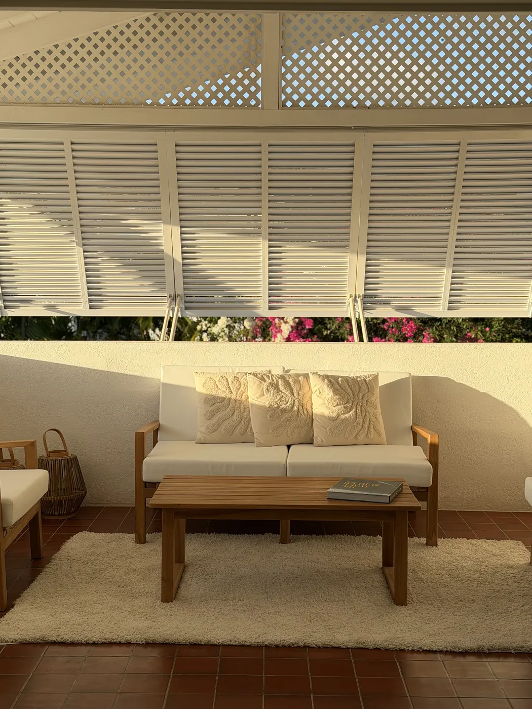 The upstairs patio with a white sofa under open shutters and bougainvillea