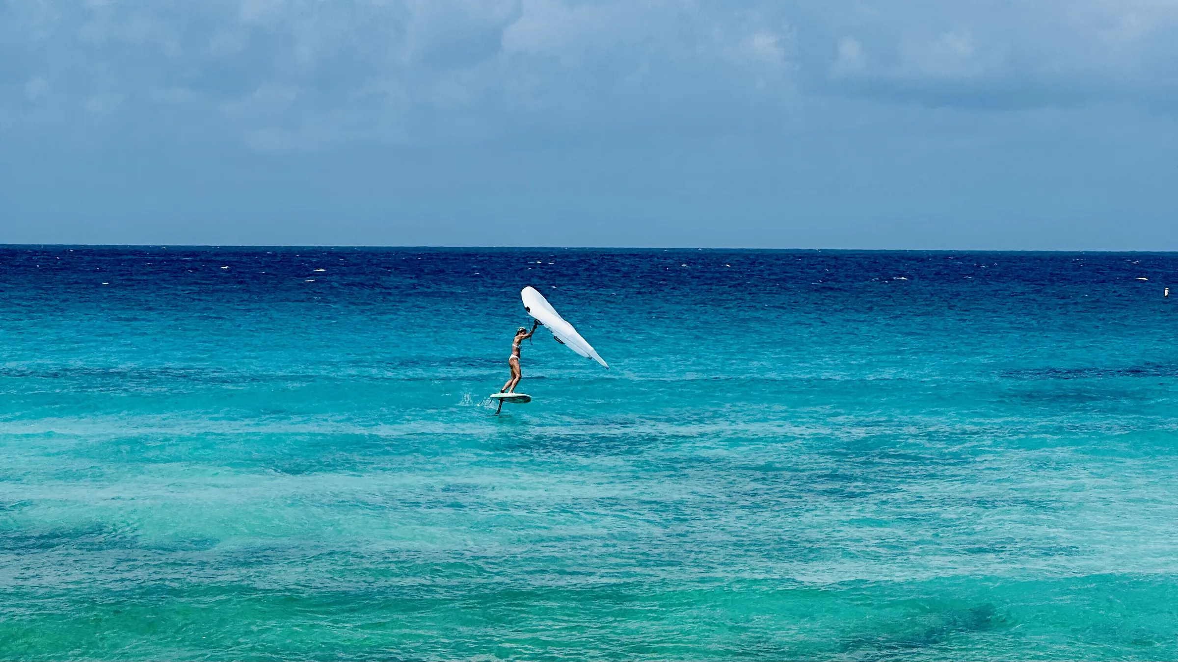 A wingfoiler flying over the turquoise water off the south coast of Barbados